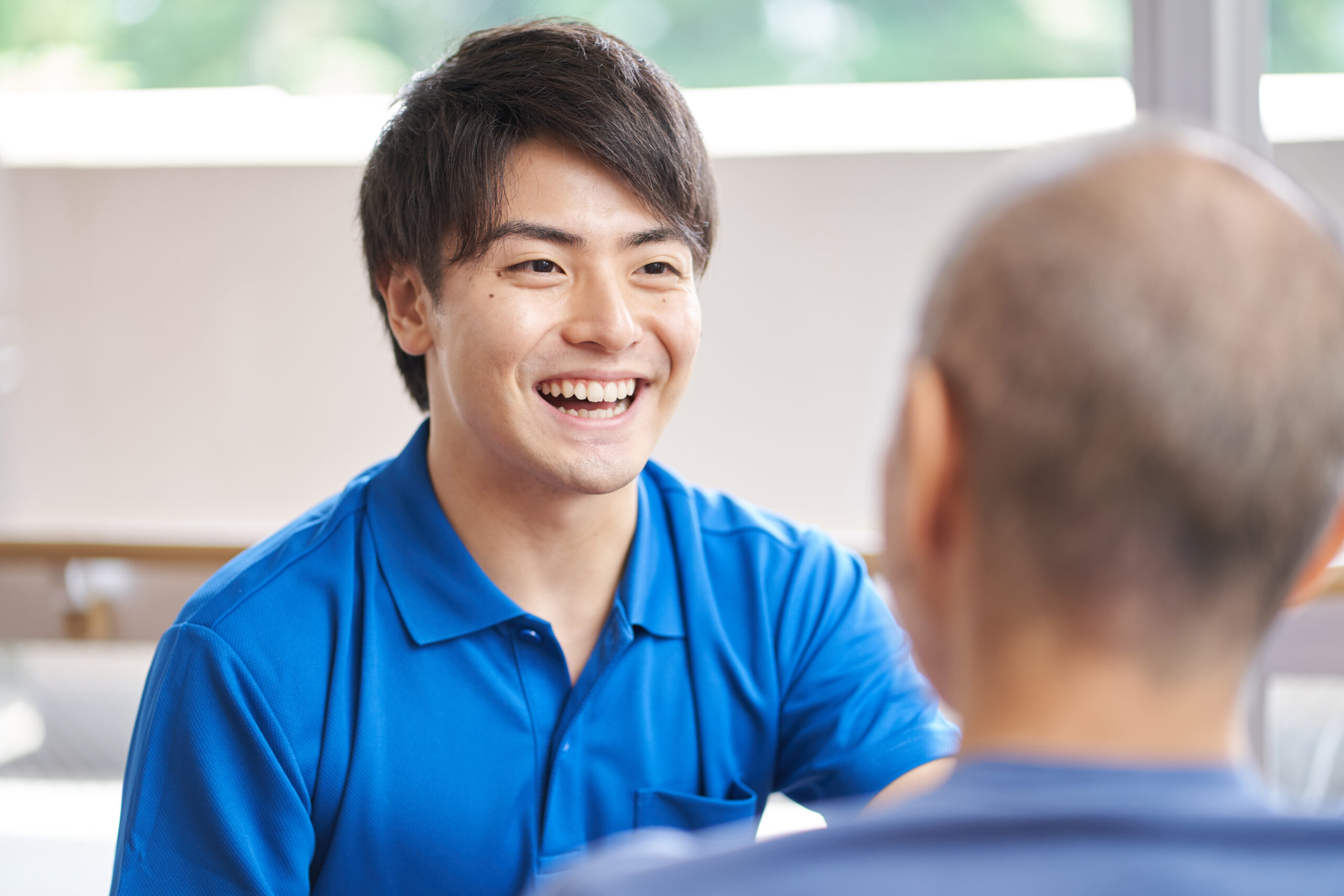 高齢者の話を笑顔で聞く介護士の様子